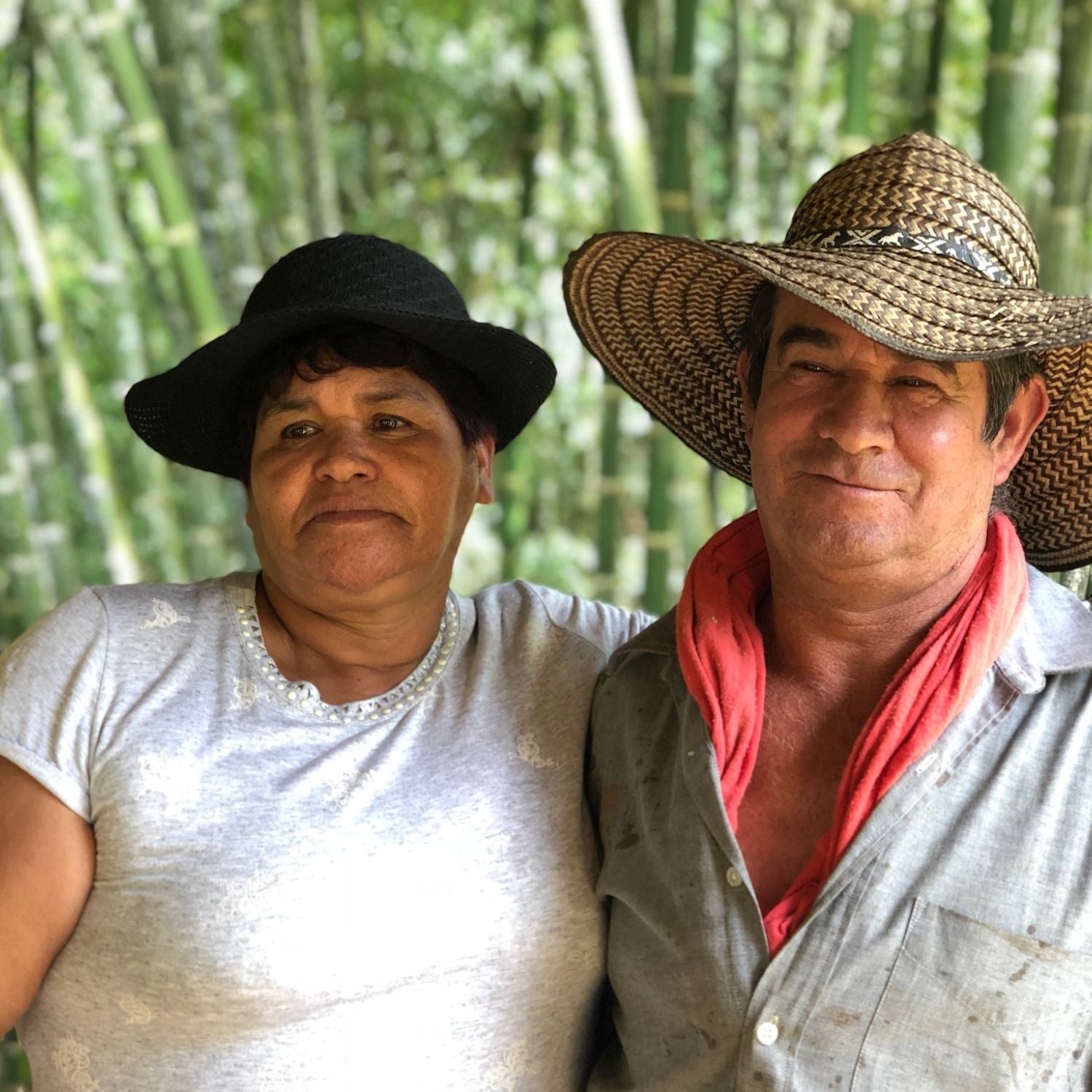 Aidé and Pedro Garro standing arm-in-arm on their Colombian coffee farm with bamboo in the background