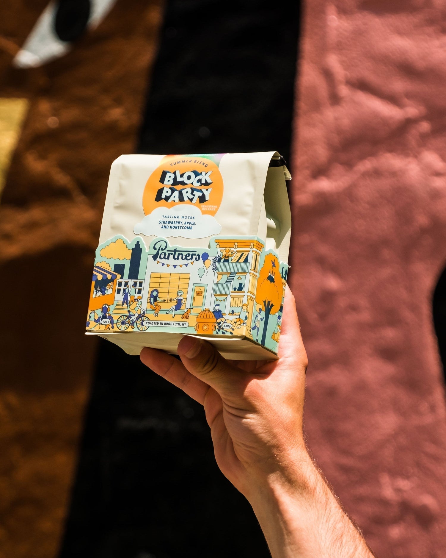 Partners Coffee image for Block Party 2025 release. This image depicts a bag of Block Party being held up against a colorful backdrop