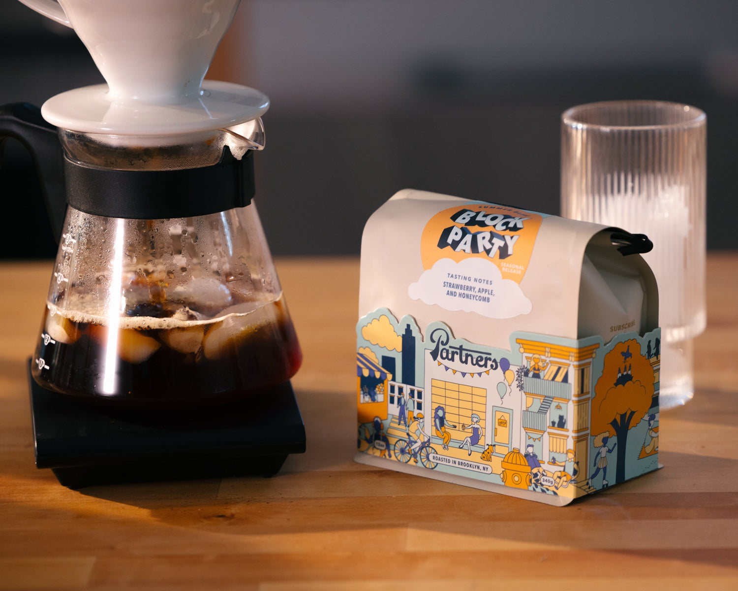 Partners Coffee image for Block Party Flash Brew recipe. This image depicts a bag of Partners Block Party next to a brewed carafe of flash brew