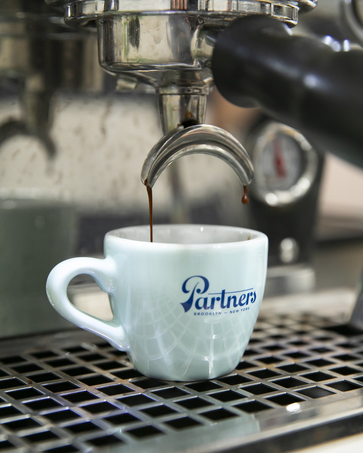 Espresso being brewed into a light blue Partners Coffee branded cup