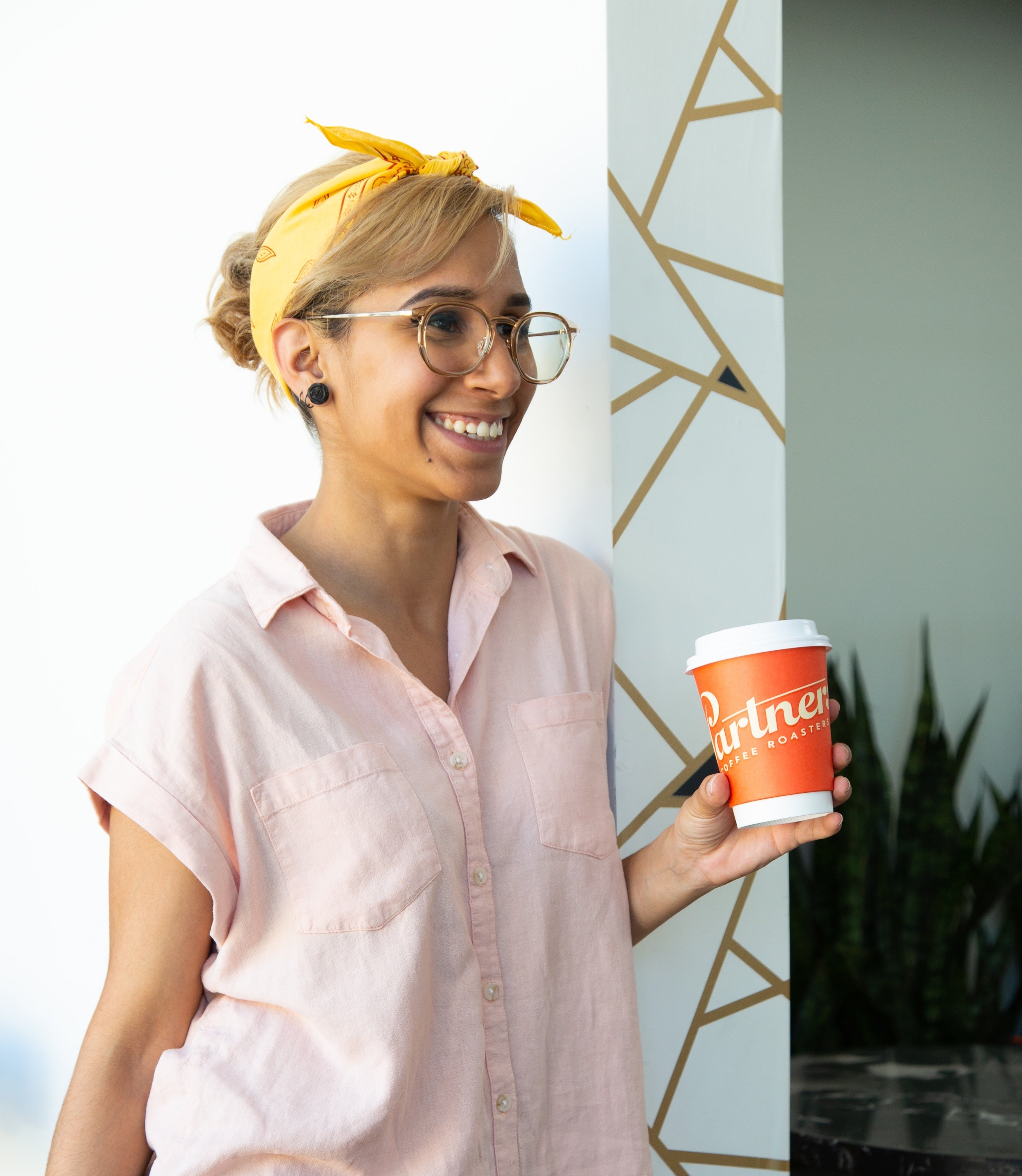 A person holding a cup of coffee and smiling
