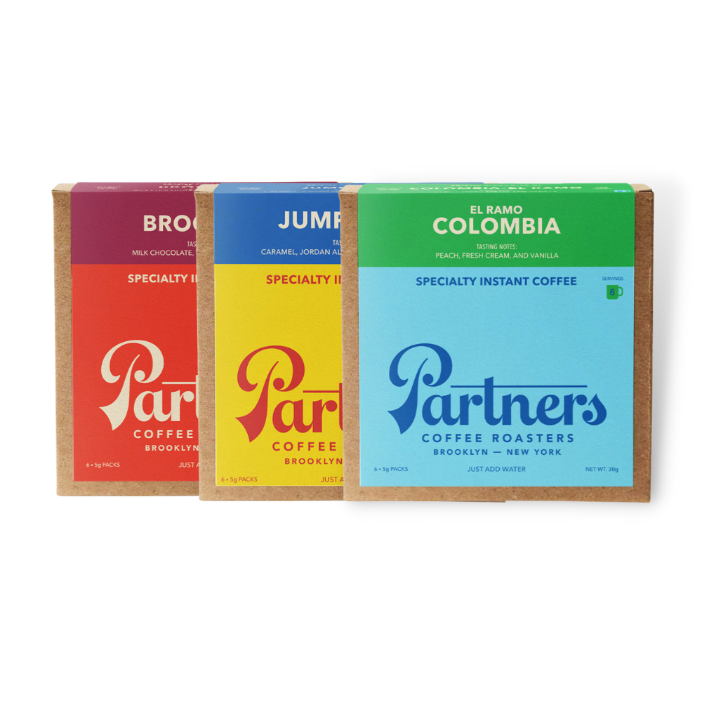 Three boxes of instant coffee sachets from Partners Coffee, with colors red, yellow, and blue, each labeled with different coffee flavors.