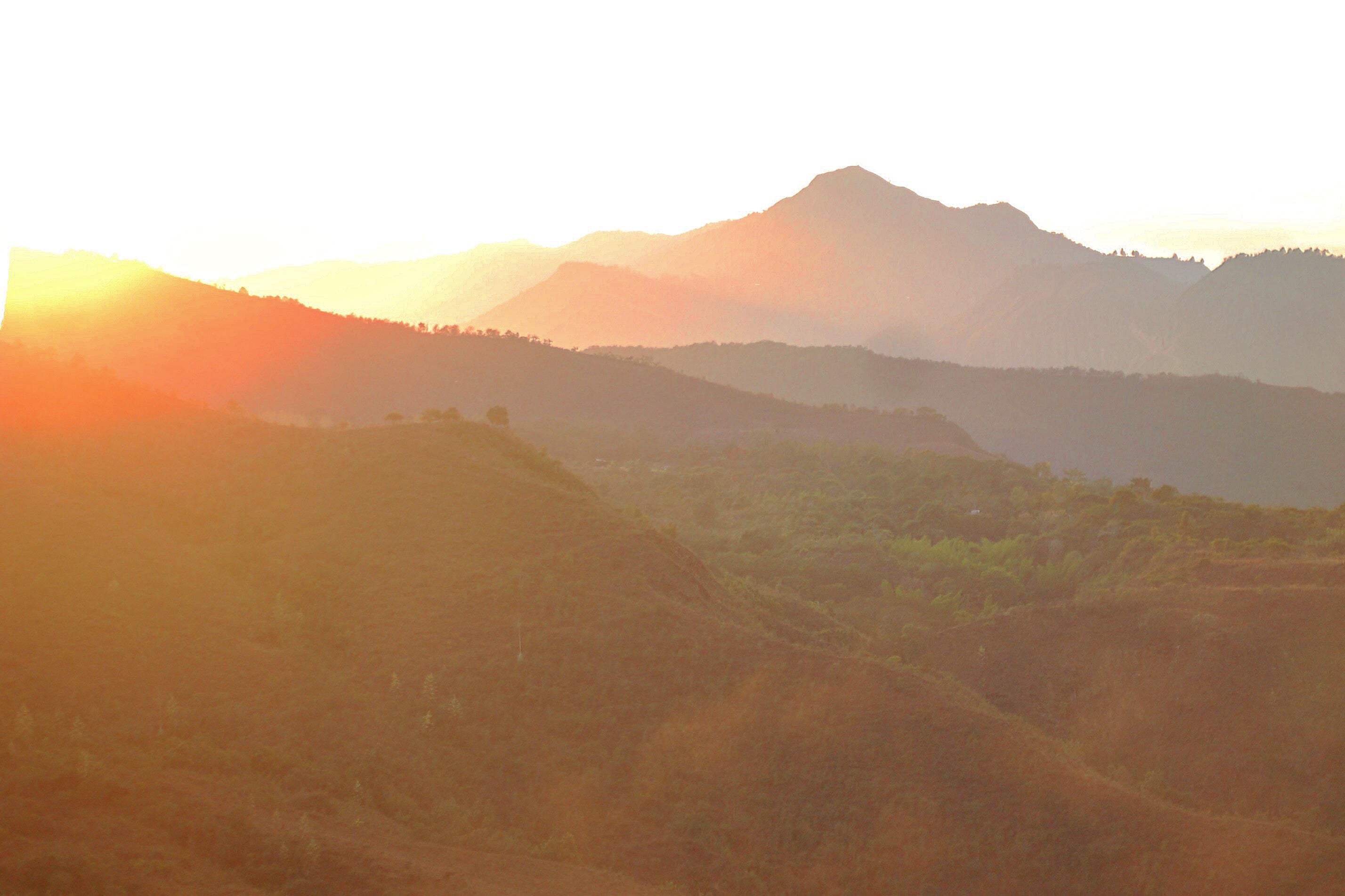 Sunrise over rolling hills and layered mountain ridges in Colombia, warm orange light illuminating the landscape