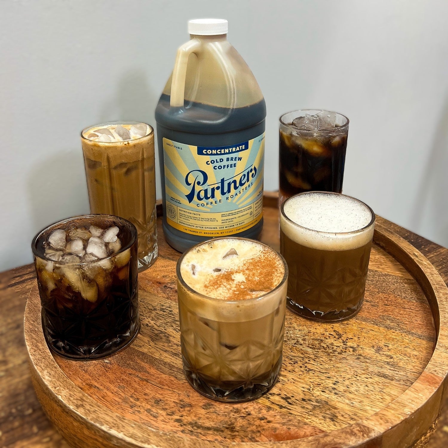 Partners Coffee Mega Jug cold brew concentrate on a wooden tray with five different preparations