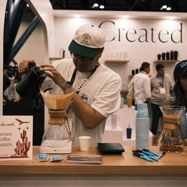 Partners Coffee Director of Coffee brewing a Chemex pour over at Created Co.'s booth at the 2025 SCA Specialty Coffee Expo